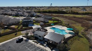A resort-style pool with shaded lounge areas and a clubhouse in The Villages at Schwertner Ranch by D.R. Horton (Jarrell, TX).