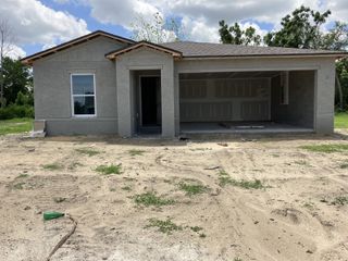 Street view A modern gray stucco home with an unfinished yard in Spring Hill Classic by Century Complete (Spring Hill, FL).