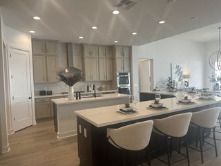 A modern kitchen features dual islands with quartz countertops, sleek cabinetry, stainless steel appliances, and recessed lighting.