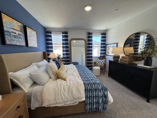 A cozy bedroom with blue accents, stylish decor, plush bedding, and ample natural light for a serene and inviting atmosphere.