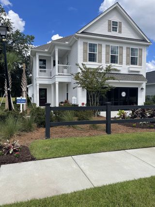 Street view A charming two-story white house with a landscaped yard in Six Oaks by Mungo Homes, Summerville, SC.