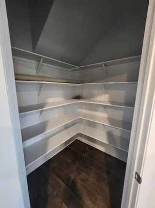 A spacious walk-in closet with dark wood flooring and white shelving for ample storage and organization.