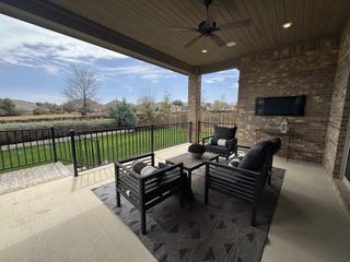 Model Home A covered patio with cozy seating, a ceiling fan, and a mounted TV, perfect for outdoor relaxation and entertaining.