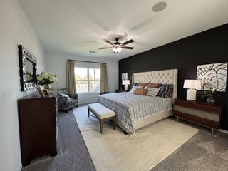 A spacious bedroom featuring a tufted bed, polka-dot chair, dark accent wall, and elegant decor with natural light filtering through.