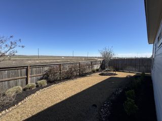 Model Home A picturesque backyard with a wood fence and open field views in Dauer Ranch by Legend Homes (New Braunfels, TX).