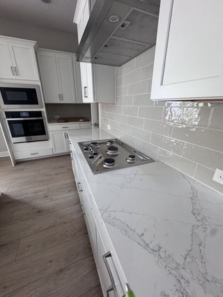 Model Home A modern kitchen with sleek white cabinetry, marble countertops, and stainless steel appliances.