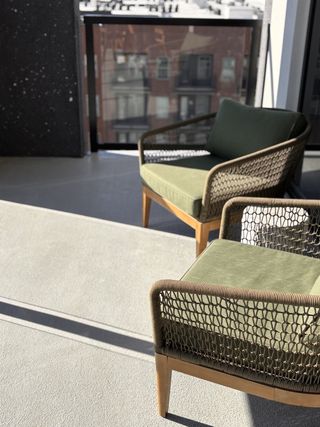 A cozy balcony with modern woven chairs and soft cushions, ideal for relaxation in urban surroundings.