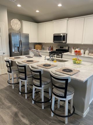 Model Home A modern kitchen with white cabinets, a sleek gray countertop island, and stylish seating for four.