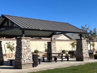 Community Amenities Charming stone pavilion with picnic tables in Northern Farms by Landsea Homes, Waddell, AZ, perfect for outdoor gatherings.
