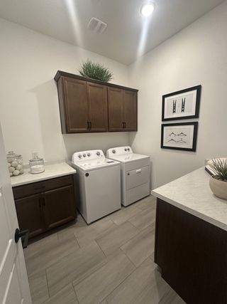 A modern laundry room with sleek tile flooring, dark wood cabinets, and spacious countertops.