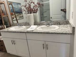 A modern bathroom with a double granite vanity, white cabinetry, and elegant decor.