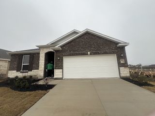 A charming brown brick home with white accents in Heartland Signature by KB Home (Heartland, TX).