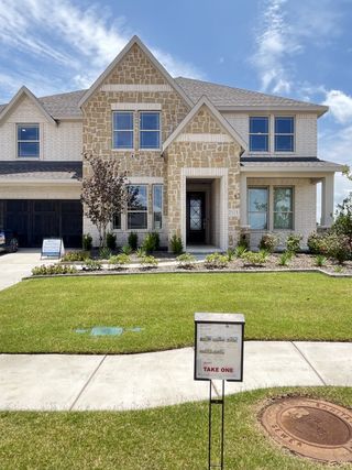 A charming stone and brick facade home with manicured landscaping in Stone River Glen 60s by Bloomfield Homes (Royse City, TX).