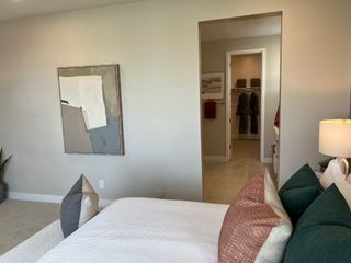 A cozy bedroom with abstract art, plush pillows, and a view into a spacious walk-in closet featuring elegant robes.