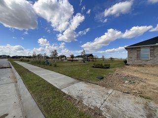 Street view Charming neighborhood street view with lush greenery in Sweetgrass Village: Landmark Collection by Beazer Homes (Crosby, TX).