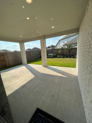 Model Home A covered patio with brick pillars overlooks a private fenced yard, perfect for outdoor gatherings.