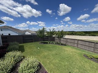 Street view A lush backyard with manicured lawn and wooden fencing in Cloverleaf by Brohn Homes (Austin, TX).