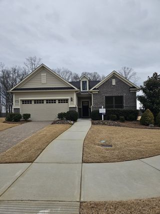 A charming brick-front home with manicured lawn in Del Webb Chateau Elan by Del Webb, Hoschton, GA.