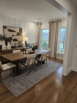 A formal dining room with wood panel accents, elegant lighting, and large windows that bring in natural light.