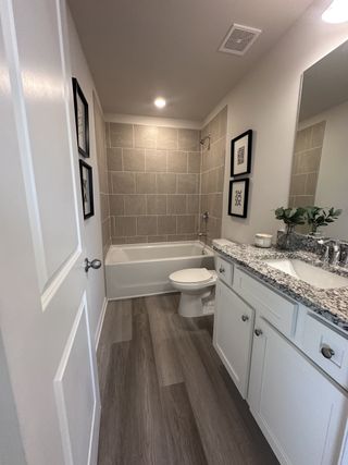 A modern bathroom featuring a sleek tub, elegant gray tiles, and a granite vanity with stylish decor accents.