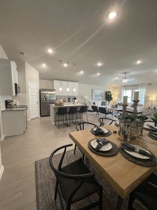 An open-concept living area with modern kitchen, dining table, and cozy living space featuring sleek lighting and decor.