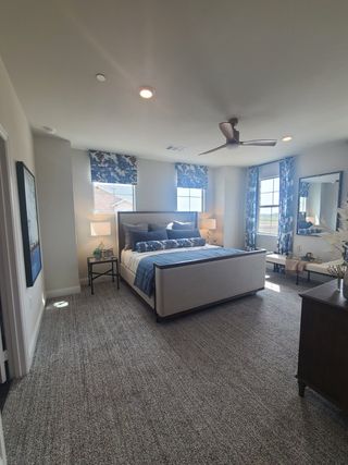 Model Home A cozy bedroom featuring blue and white decor, plush carpet, and ample natural light from large windows.