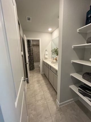 A modern bathroom featuring a sleek vanity, decorative shelving, and elegant tiled flooring for a touch of sophistication.