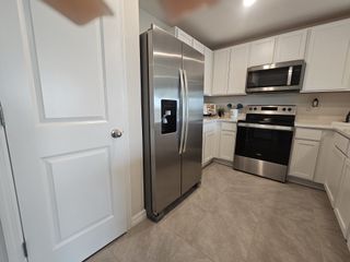 Model Home A modern kitchen with stainless steel appliances, white cabinets, and elegant tile flooring.