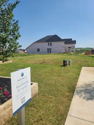 A modern home under construction with lush landscaping in Hazelwood by Normandy Homes (Frisco, TX).