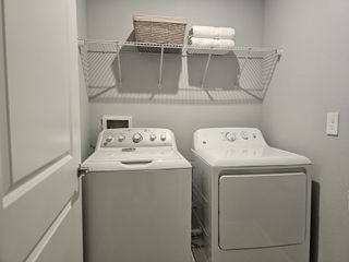 A functional laundry room with a washer, dryer, and overhead shelving for efficient organization.