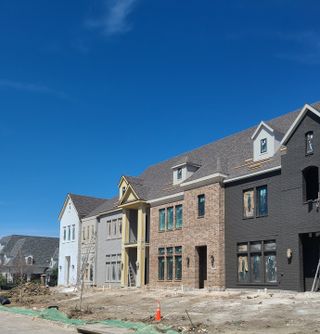 Street view Newman Village by Centre Living Homes features elegant multi-toned brick townhomes in Frisco, TX.