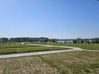 Community Amenities A scenic view of greenery and water in the Bayside community by Beazer Homes in Rowlett, TX, with modern apartments nearby.