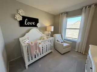 A cozy nursery with neutral tones, featuring a white crib, plush armchair, and soft lighting for a serene atmosphere.