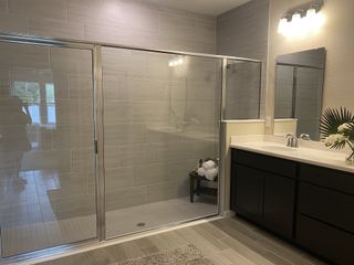 A modern bathroom featuring a spacious glass shower, sleek black vanity, and elegant lighting.