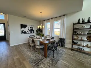 Model Home A contemporary dining area with a sleek wooden table, elegant decor, and modern lighting, framed by large windows.