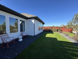 A lovely white siding home with a cozy patio and lush yard in Sunfield by David Weekley Homes (Buda, TX).