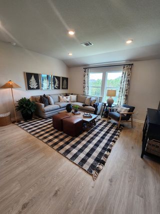 A cozy living room with plaid decor, modern furniture, and large windows bringing in natural light.