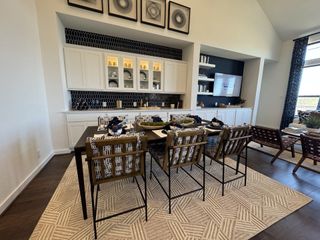 A chic dining room with a large table, patterned chairs, and a stylish black-tiled backsplash.