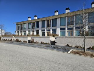 A row of elegant modern townhomes with large windows, balconies, and a sleek exterior design.
