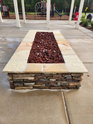 Community Amenities A chic outdoor stone planter filled with lava rocks, set near a playground, adding charm and function to the recreational area.