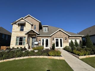 Street view A beautiful brick and stone home with lush landscaping in Provence 70s by Ashton Woods (Austin, TX).
