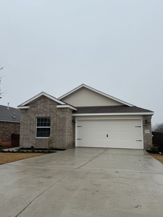 A modern brick home with a spacious driveway in Lively Ranch: Highlands Collection by Lennar (Georgetown, TX).
