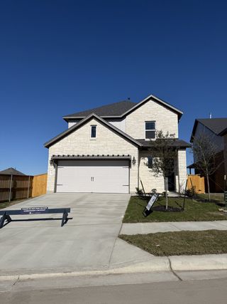 Street view A modern stone-accented home with a tidy lawn in Cedar Brook by M/I Homes (Leander, TX).