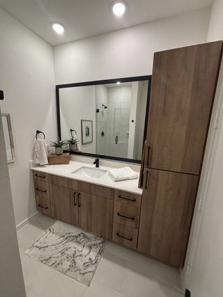Model Home A modern bathroom with a sleek wooden vanity, large mirror, and minimalist decor.