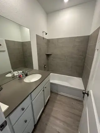 A modern bathroom featuring a sleek vanity, neutral tiles, and a spacious tub for a clean, contemporary look.