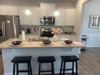 A modern kitchen featuring granite countertops, stainless steel appliances, and stylish pendant lighting.