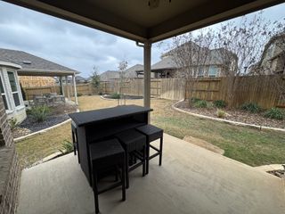 Model Home A spacious backyard with a mix of grass, trees, and stone-lined landscaping in Sendero at Veramendi by Pulte Homes (New Braunfels, TX).