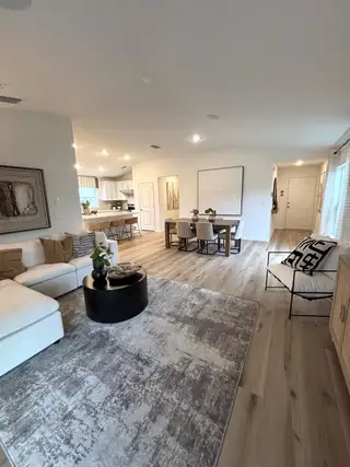 An open-concept living space with chic decor, featuring a cozy rug, elegant furniture, and seamless flow into the dining area.