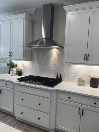 A modern kitchen with sleek white cabinetry, a chic backsplash, and stainless steel range hood.