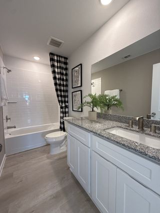 Model Home A modern bathroom with sleek granite countertops, a checkered shower curtain, and elegant decor.